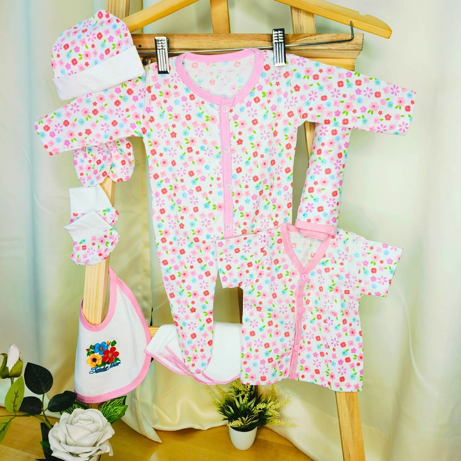 Cutetales Baby clothing set with floral pattern on a wooden hanger against a light background