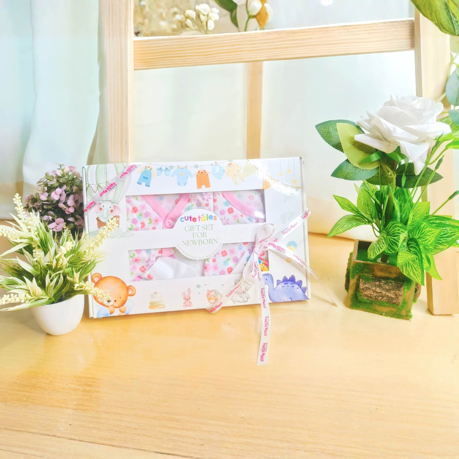 Cutetales Baby gift set with cartoon characters on a wooden surface with plants