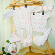 Cutetales Baby clothing set with heart patterns on a wooden rack against a light background