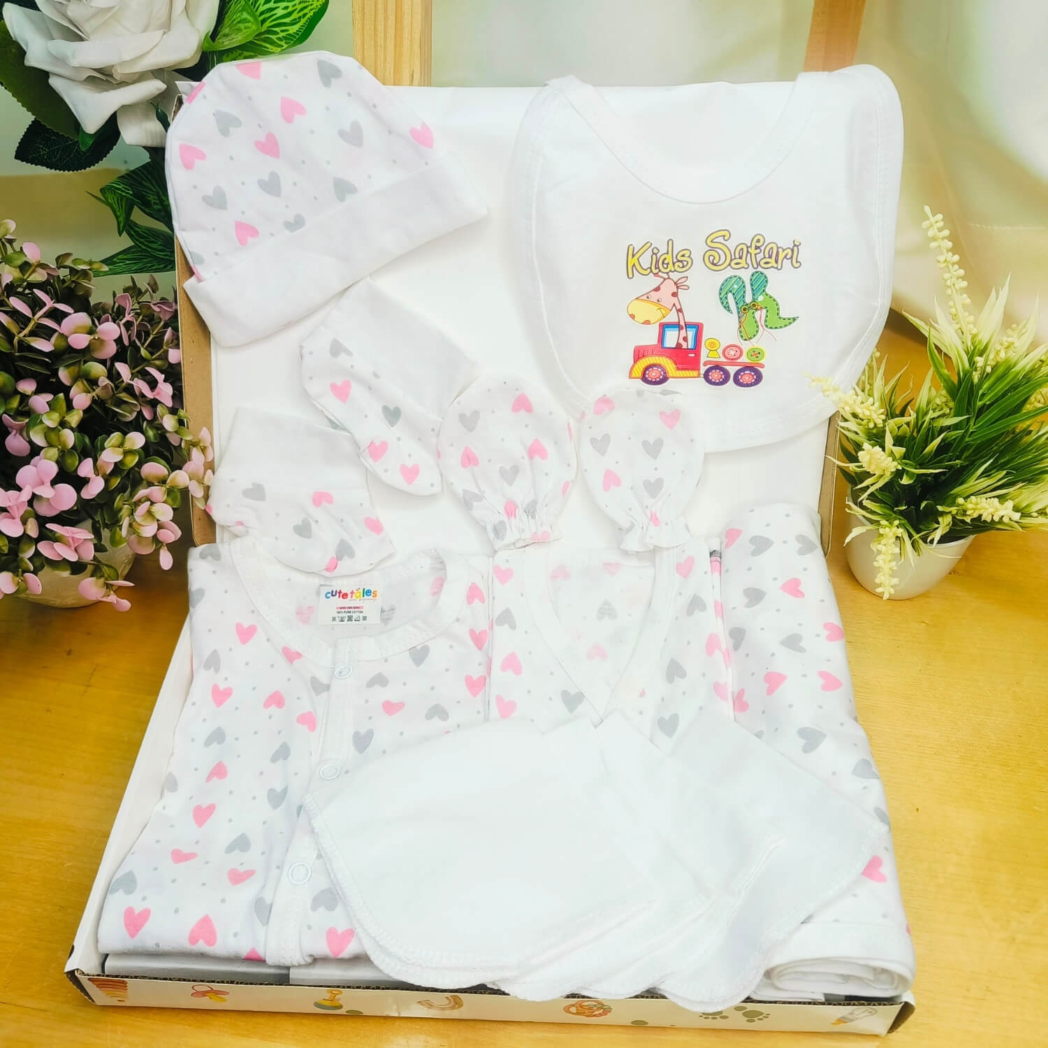 Cutetales Baby wrap with heart pattern and 'Kids Safari' branding on a wooden surface with plants.