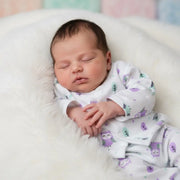 Newborn baby sleeping in a crib with owl-patterned pajamas