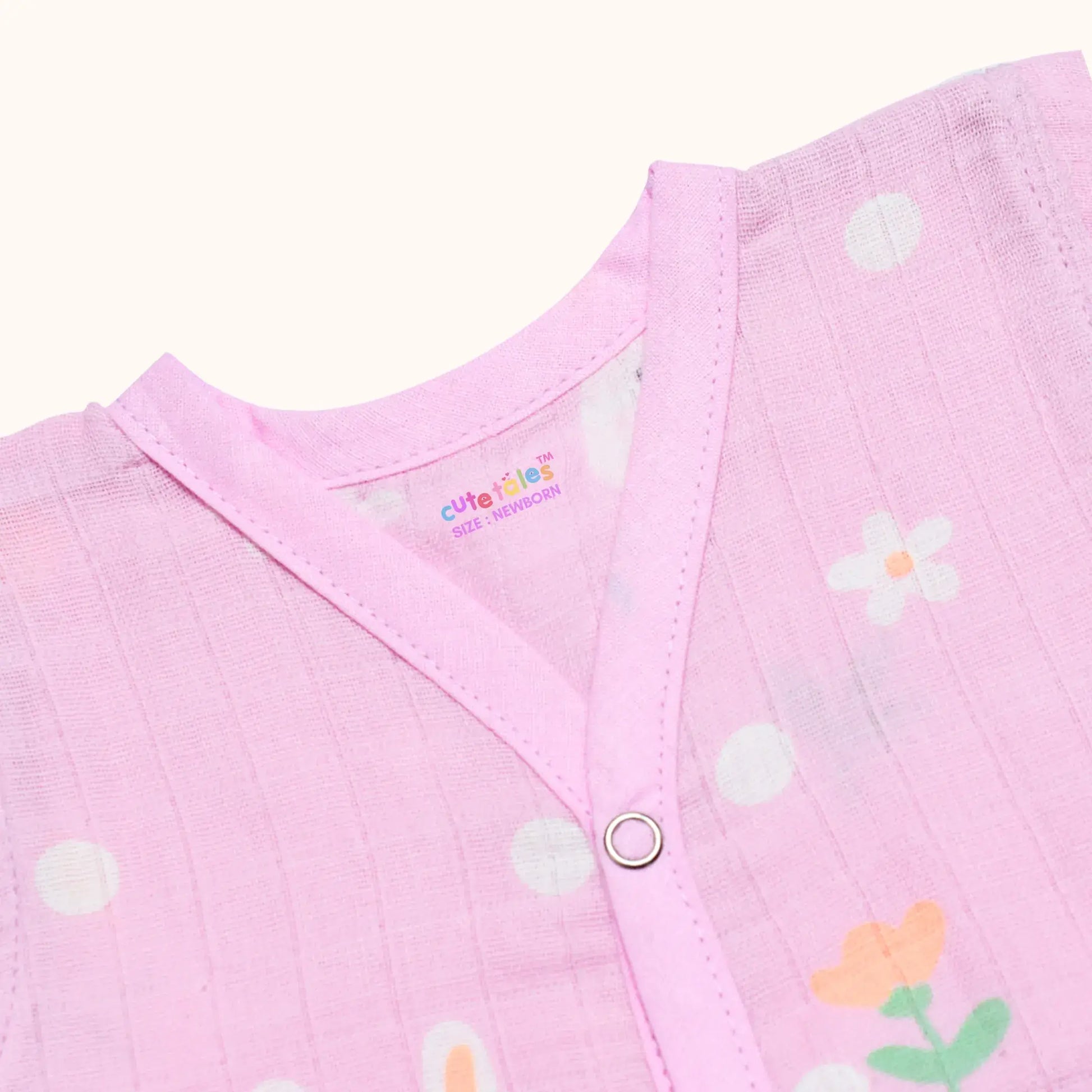 Close-up of a pink baby outfit with floral patterns and a visible brand logo.