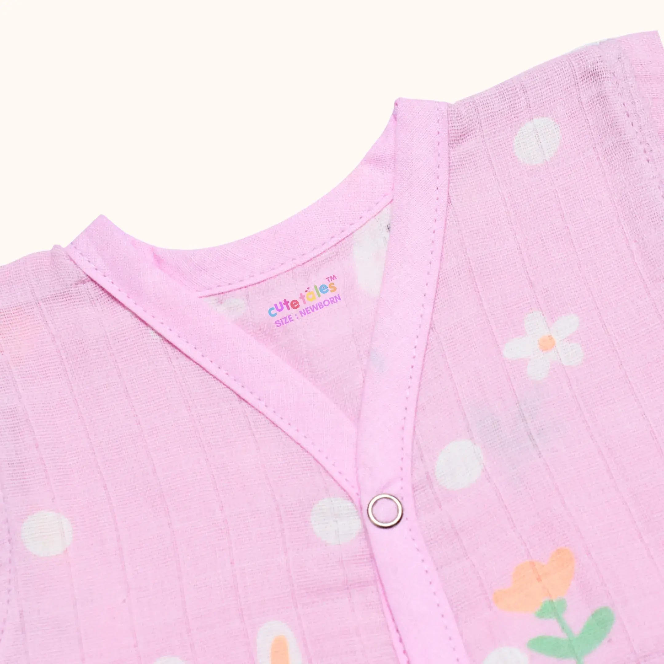 Close-up of a pink baby outfit with floral patterns and a visible brand logo.