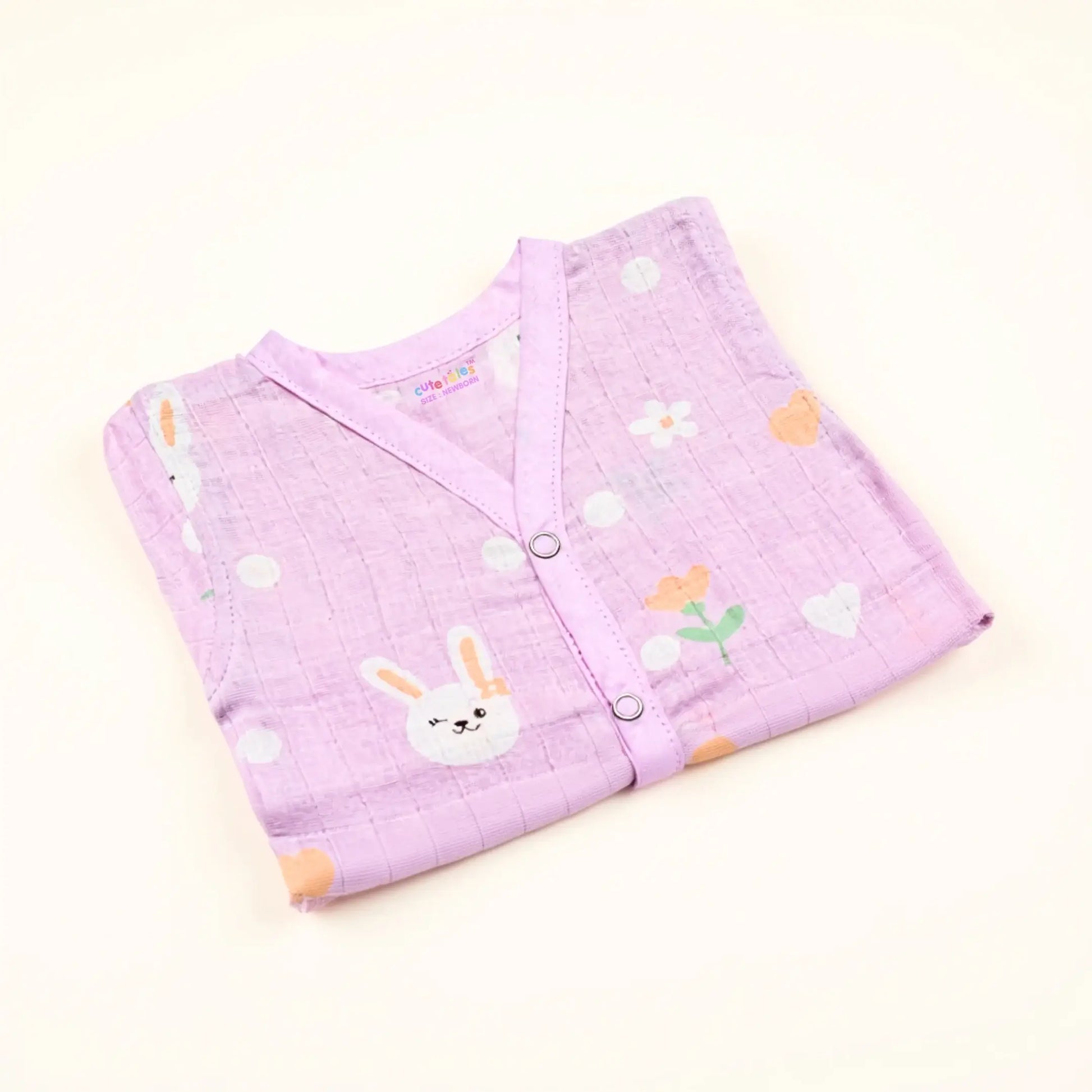 Folded purple baby blanket with cartoon designs on a light beige background