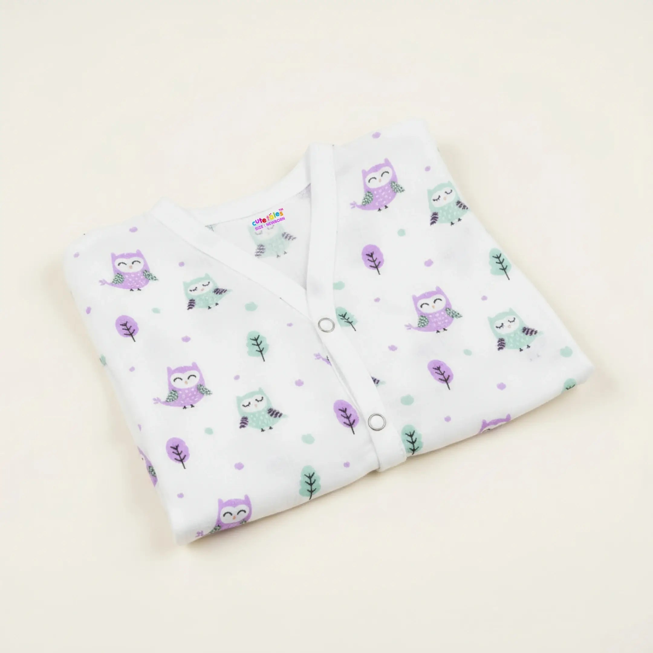 Folded baby outfit with owl pattern on a light beige background