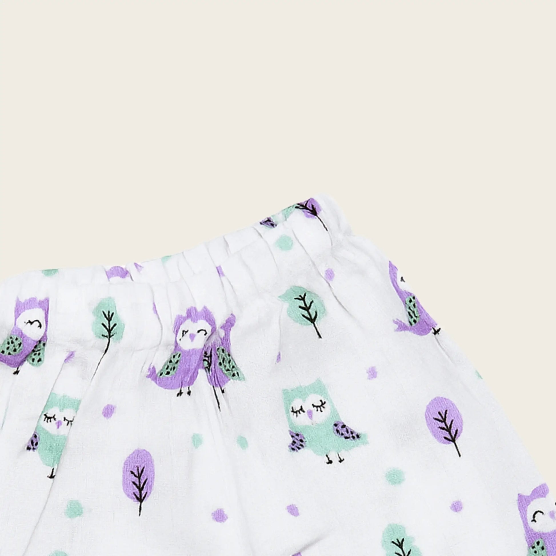 Fabric with purple and green owl pattern on a beige background